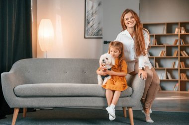 Anne ve kızı evde Malta köpeğiyle birlikte..