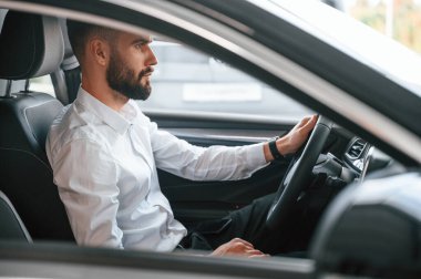 Test sürüşü. Beyaz elbiseli genç adam araba galerisinde..