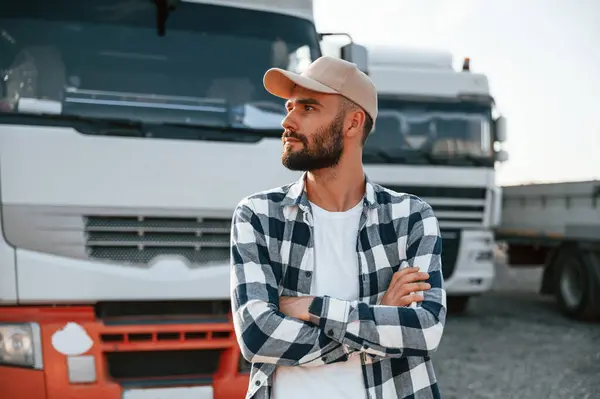 stock image With arms crossed. Young truck driver is with his vehicle at daytime.