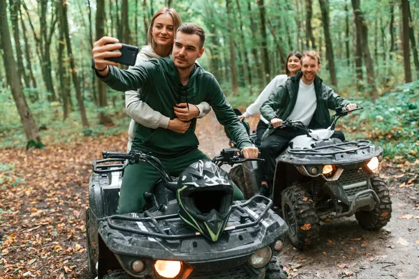 stock image Making a selfie by smartphone. Two couples on a quad bike in the forest during the day.