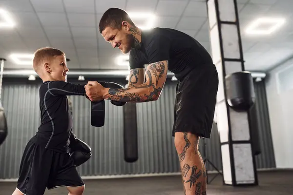 stock image Standing and learning how to punch. Coach is teaching the boy box techniques indoors.