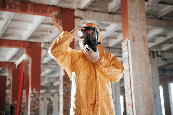 Man dressed in chemical protection suit in the ruins of the post apocalyptic building.