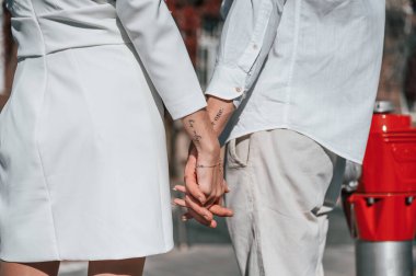 Ellerinde dövmeler var. Onun tek. Güzel genç çift sokakta eski binaya karşı birlikte..