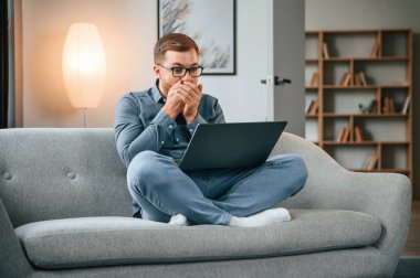 Şok oldum. Erkek serbest çalışan evde dizüstü bilgisayar kullanıyor. Konforlu daire.