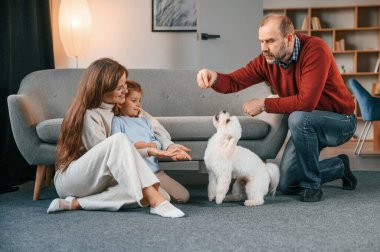 Adam malta köpeğiyle oynuyor. Anne ve kızı izliyor..