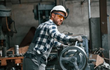 Endüstri makinesini manipüle etmek. Üniformalı fabrika çalışanı içeride..
