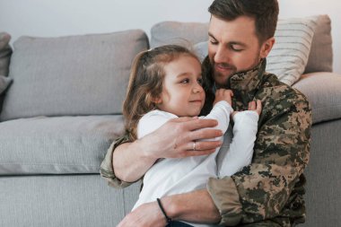 Savunma ve güvenlik kavramı. Üniformalı asker küçük kızıyla evde..