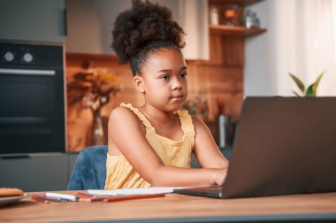 Laptop kullanıyorum. Gündüz vakti evde rahat giyinen sevimli siyah kız var..