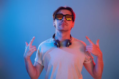 Showing gestures. Man standing in the studio with neon light.