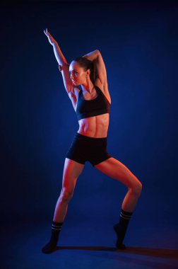 Duruyorum, poz veriyorum. Güzel kaslı kadın stüdyoda neon ışıklı..