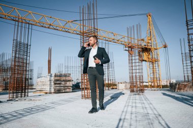 Telefonla konuşuyorum. Resmi kıyafetli bir işadamı gün içinde şantiyede olacak..