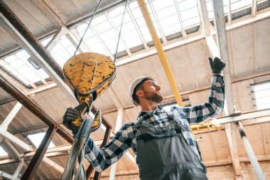 Vinçle çalışmak. Üniformalı bir fabrikadaki adam içeride..