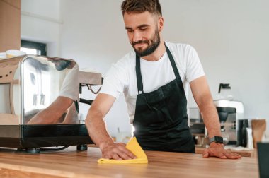 Temizlik masası. Beyaz gömlekli ve siyah önlüklü kafe çalışanı içeride..
