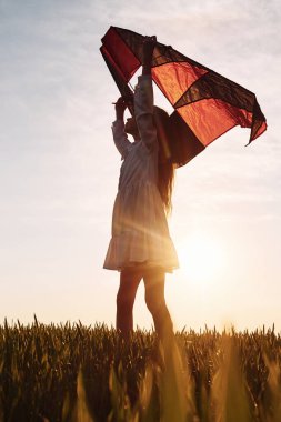 Bir çocuğun elinde güzel güneş ışığı ve uçurtma. Mutlu kız yazın dışarıda gezintiye çıkar..