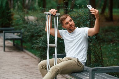 Koltuk değnekli adam dışarıdaki parkta. Bacağımdan yaralandı..