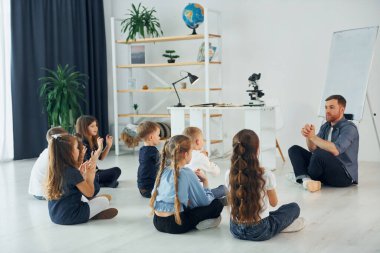 Adam jest dili öğretiyor. Okulda öğretmenle birlikte bir grup çocuk öğrenci..
