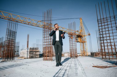 Telefonla konuşuyorum. Resmi kıyafetli bir işadamı gün içinde şantiyede olacak..