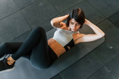 Karın kasları egzersizi yapıyorum. İnce vücutlu spor elbiseli kadın spor salonunda..