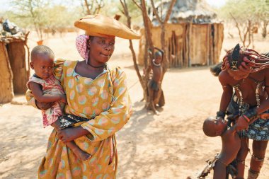 Namibya, Afrika - 14 Haziran 2021: Afrika 'daki etnik halk açık havada. Yetişkin kategorisi. Yakın evler.