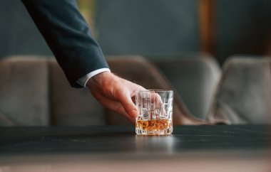 Masadan bir bardak alkollü içecek alan adamın elini kapat..