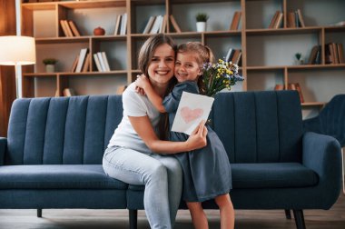 Birbirinize sarılın. Hediyeyi veriyorum. Genç anne kızıyla birlikte dairede..