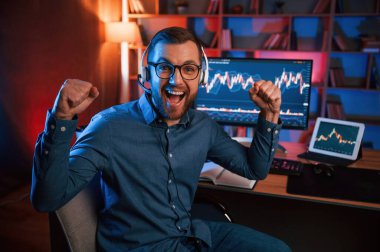 Happy borsa simsarı içeride bilgisayar başında çalışıyor ve başarıyı kutluyor. Değişim ve para kavramı.