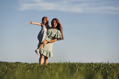 Kızı ellerimle tutuyorum. Anne ve kızı yazın açık havada eğleniyorlar..