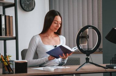 Profesyonel ışıklandırma. Çevrimiçi ana sınıf. Beyaz elbiseli genç ve güzel bayan ofiste..