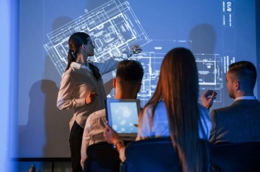 Planı projektörde gösteriyorum. Kadın lider borsa şirketinde çalışanlarla konuşuyor..