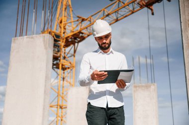 Not defterini tutuyorum. Üniformalı adam inşaat alanında çalışıyor..