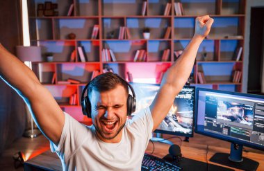 Ellerinizi kaldırın, zaferi kutlayın. Günlük giysiler içindeki erkek oyun flaması içeride bilgisayar ile birlikte..