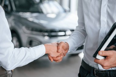 Tokalaşmanın yakın görüntüsü. Beyaz elbiseli bir adam araba galerisinde birlikte..