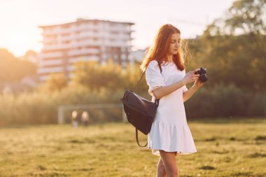 Profesyonel kamera ellerinde. Genç kız güneşli bir günde sahada güzel bir hafta sonu geçiriyor..