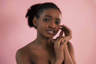 Kamera için poz vermek. Pembe arka plana karşı olan Afrikalı Amerikalı genç bir kadının portresi.