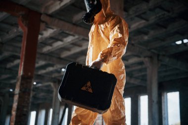 Alt manzara. Kıyamet sonrası binanın harabelerinde kimyasal koruma kıyafeti giymiş bir adam..