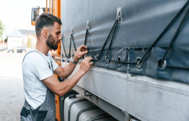 İpleri kontrol ediyorum. Üniformalı bir adam büyük bir kamyon için hizmet veriyor..