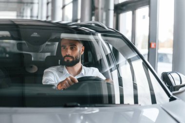 Ön manzara. Otomobilin içinde oturuyor. Beyaz elbiseli genç adam araba galerisinde..