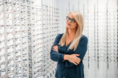 Kollarını kavuşturmuş duruyorsun. Mağazadaki kadın yeni gözlük deniyor..