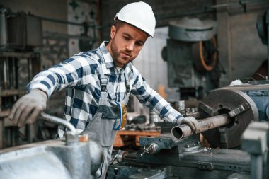Üniformalı fabrika çalışanı içeride. Endüstri makinesiyle.