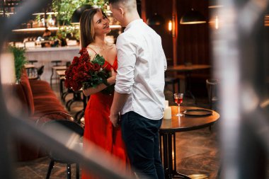 Adam güzel çiçekler veriyor. Romantik çift restoranda yemek yiyor..