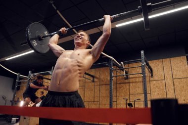 Ağırlıklar ellerde. Güçlü adam spor salonunda halteri kaldırıyor..