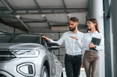 Yürüyor ve otomobili seyrediyor. Beyaz elbiseli bir adam araba galerisinde birlikte..