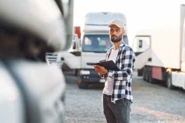 Siyah not defteriyle. Genç kamyon şoförü gündüz vakti aracıyla geliyor..