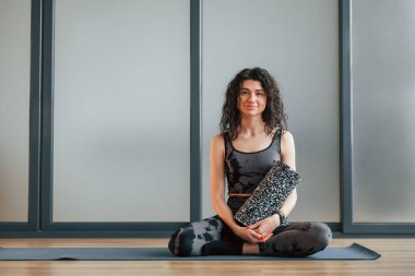 Yoga minderinde oturuyor. Spor elbiseli kadın stüdyoda..