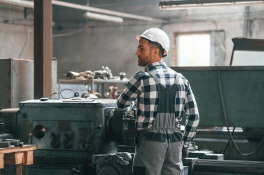 İşletim makinesi. Üniformalı fabrika çalışanı içeride..