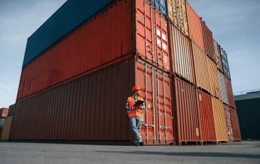 Dijital tablet ellerinde. Erkek işçi konteynırlarla birlikte olay yerinde..