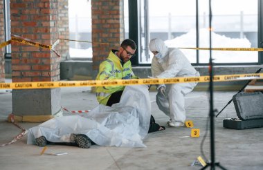 Gündüz vakti. Dedektifler cesedin yanındaki suç mahallinde kanıt topluyorlar..