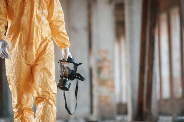 Solunum cihazı elinde. Kıyamet sonrası binanın harabelerinde kimyasal koruma kıyafeti giymiş bir adam..