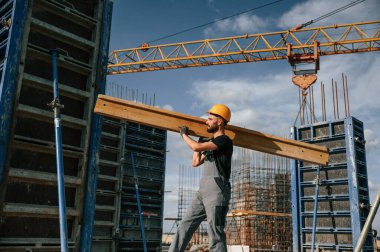 Sarı renkli ahşap tahta. Üniformalı adam inşaat alanında çalışıyor..