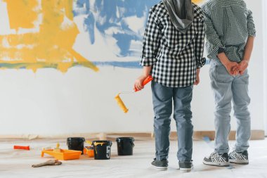 Günlük kıyafetlerle. İki çocuk ev odasında duvar boyuyor..